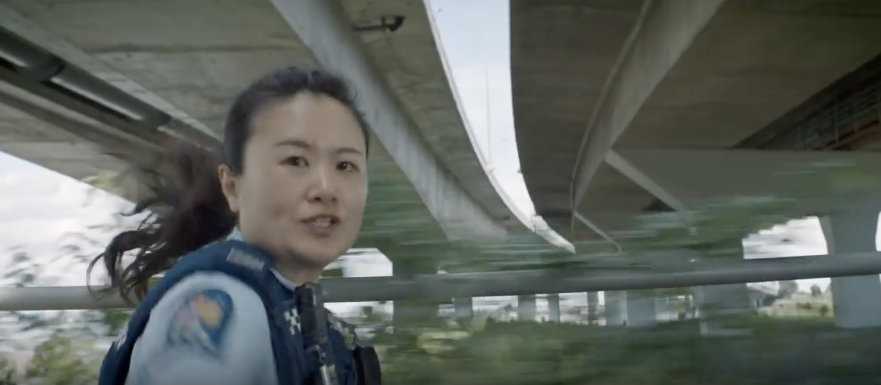 Image of woman police officer, filmed from a side profile, running-left-to-right across the screen in hot pursuit