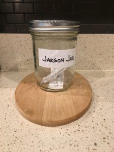 Image of sealed Jargon Jar, containing a paper with 'leverage' and a paper with 'push the envelope' sealed inside