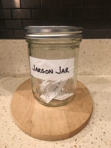 Image of the Jargon Jar with pieces of paper inside that read leverage, push the envelope, and touch base offline