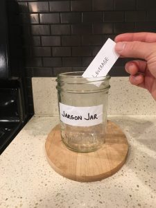 Image of a hand depositing hand-written 'Leverage' note into the Jargon Jar